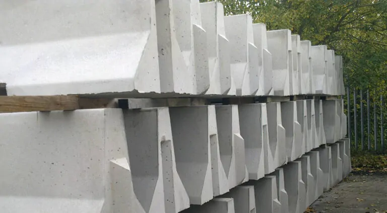 Stacked concrete barriers arranged in multiple rows, with greenery visible in the background.