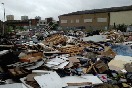 A large pile of assorted rubbish and debris in an industrial area.