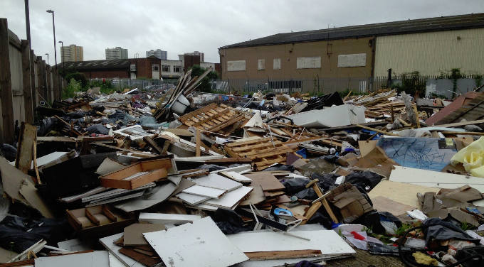A large pile of assorted rubbish and debris in an industrial area.