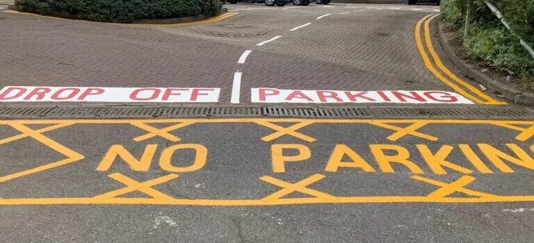Road signage indicating "No Parking" and "Drop Off Parking" with yellow and white markings.