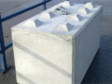 Concrete block with pyramidal protrusions on top, placed on an outdoor pavement.