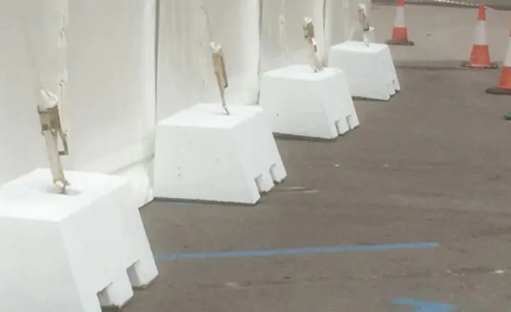 White barriers anchored with weights alongside traffic cones on a pavement.
